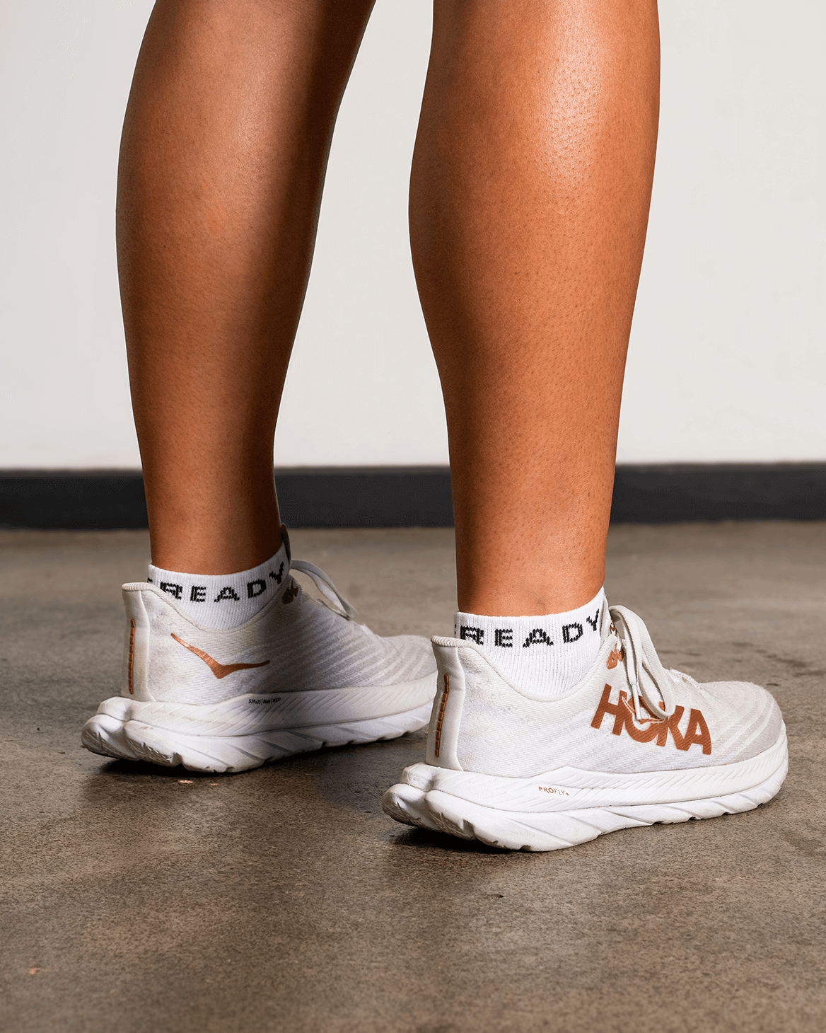 White running shoes with visible branding on a concrete floor.