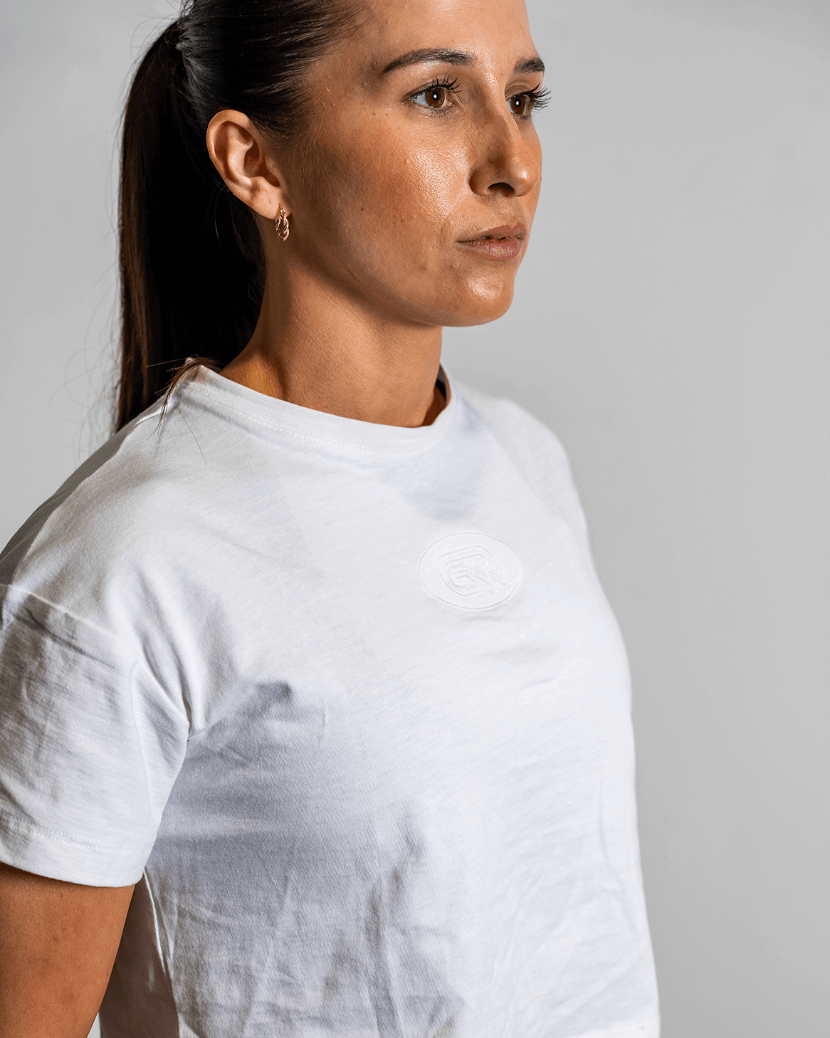 Woman wearing a white t-shirt with a visible stain on a gray background